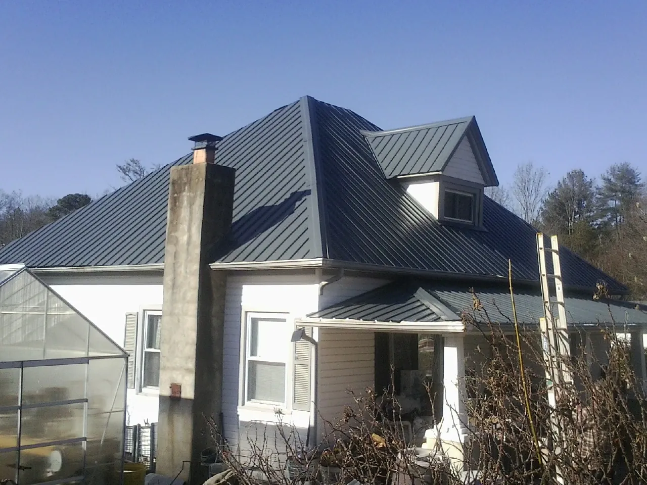 Dark blue standing seam metal roof on a white farmhouse with dormer — Slate & Tile Roof Repair by Roofing Brothers in Fort Leavenworth
