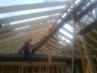 Rafters going up over a new addition with a worker on the wall in Fort Leavenworth