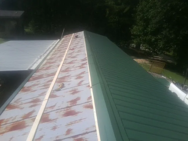Old rusted panels beside newly installed green metal roofing — Wind Damage Roof Repair by Roofing Brothers in Fort Leavenworth