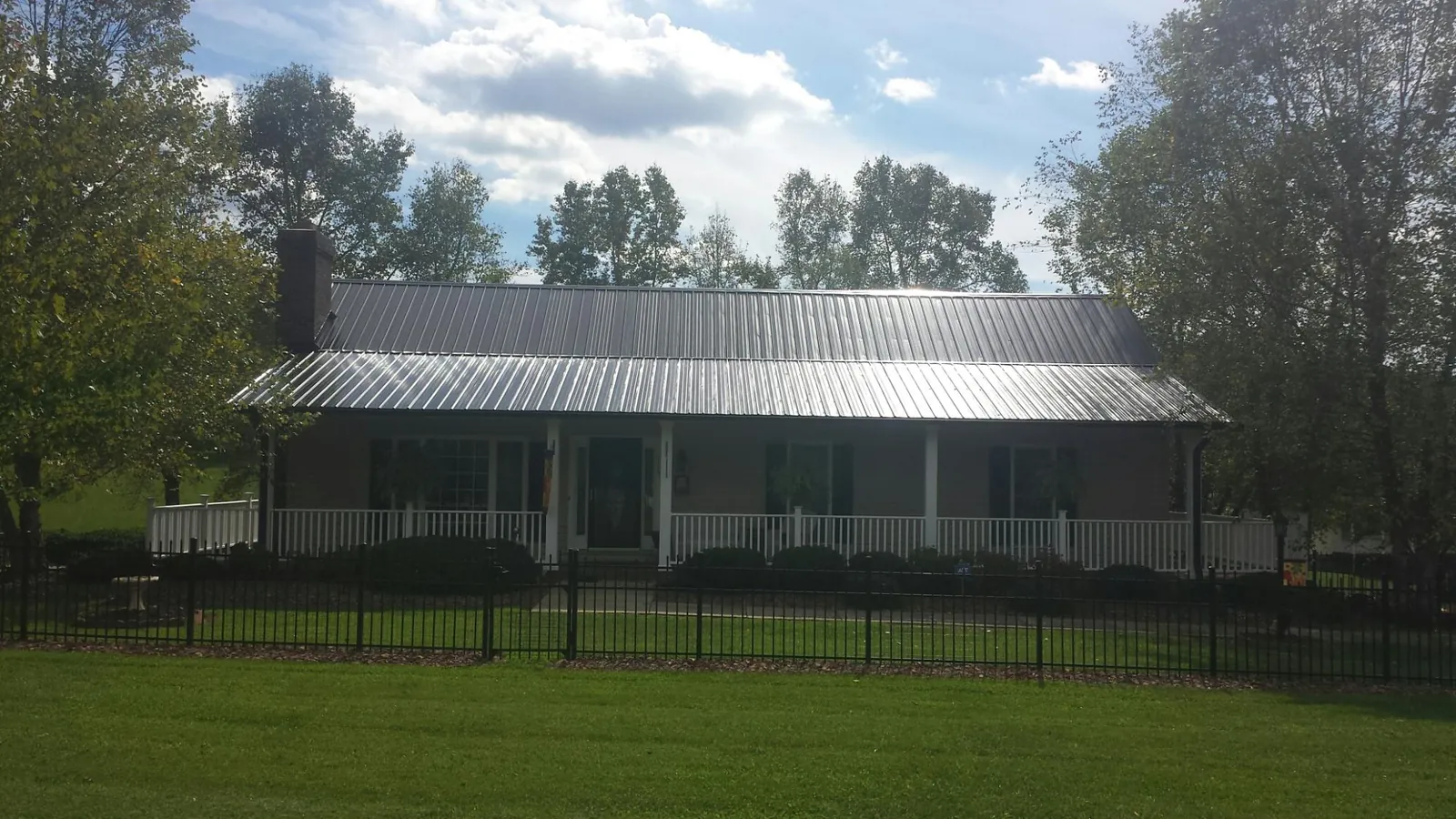 Gray metal roof on a brick ranch with a full width front porch — Gutter Guard Installation work by our crew in Fort Leavenworth