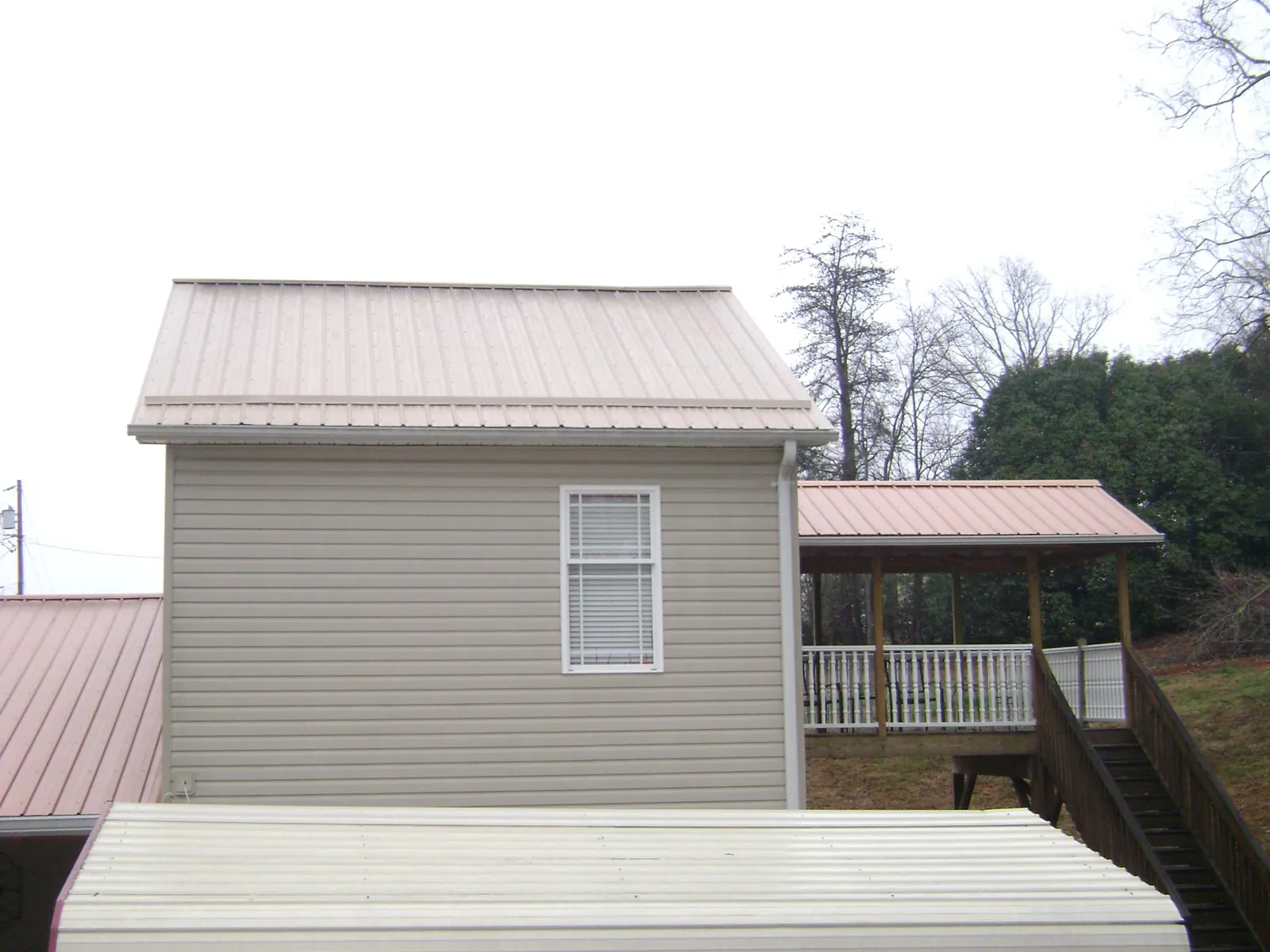 Tan metal roofs on a two story addition and attached porch, from a Roof Replacement job in Fort Leavenworth