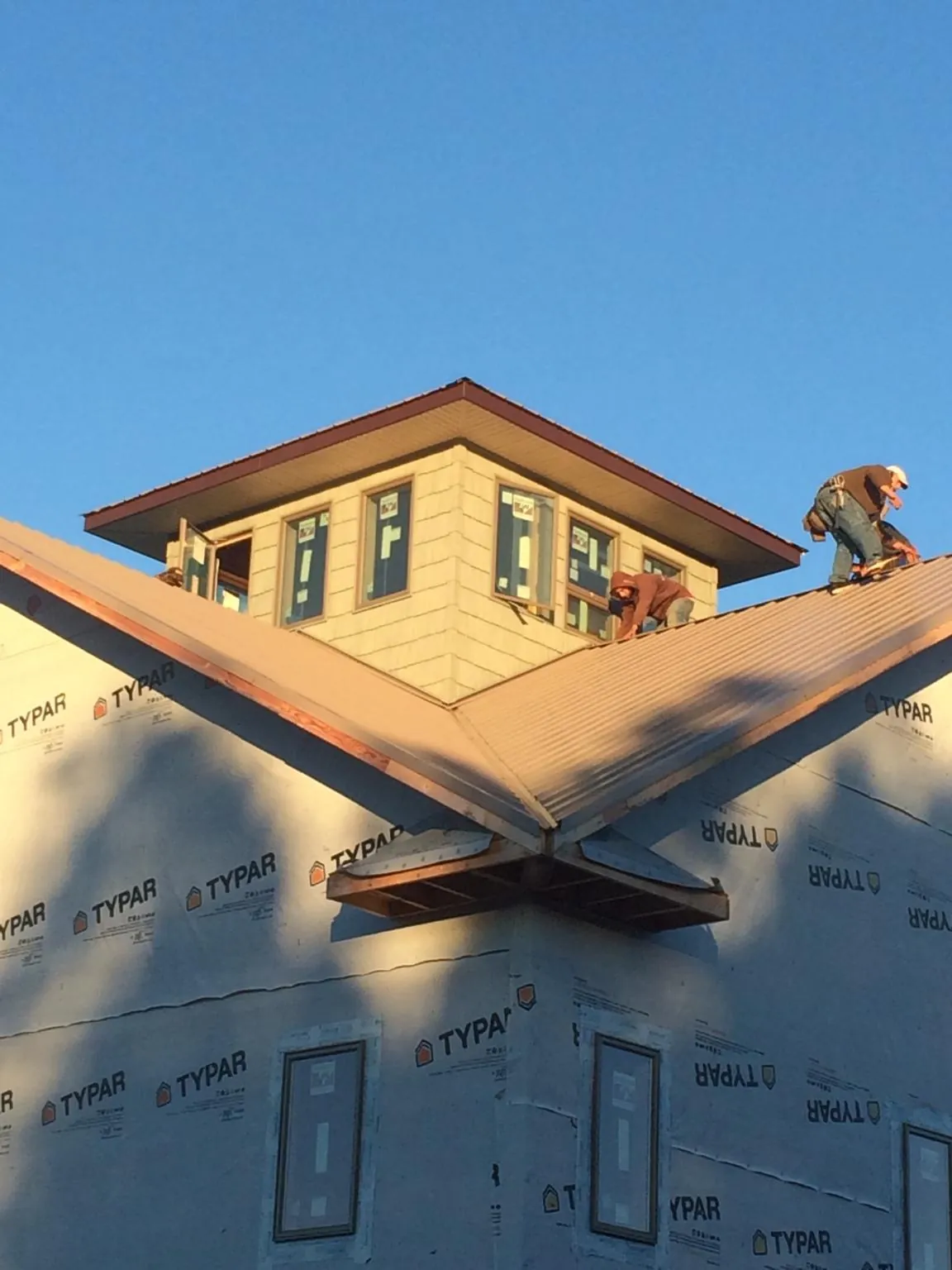 Roofers working around a rooftop cupola on a new metal roof at sunset — Roof Waterproofing in Fort Leavenworth by Roofing Brothers